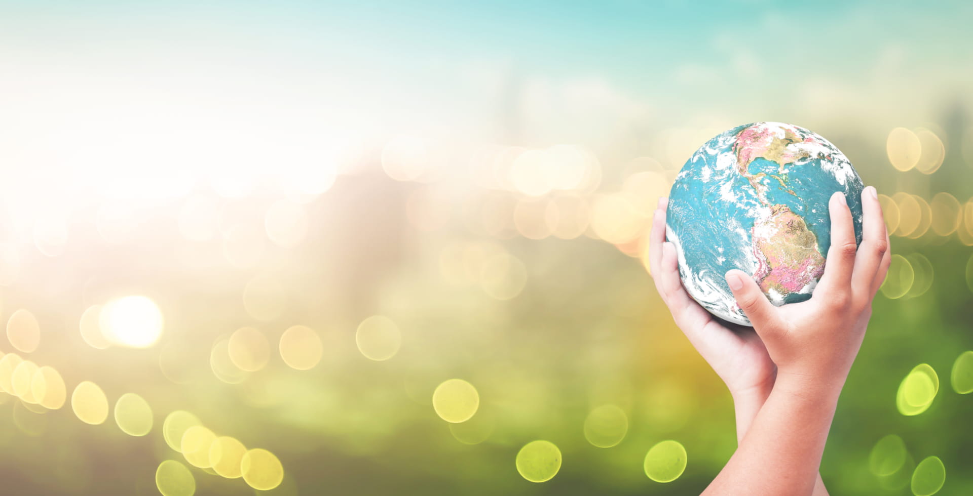 Hände halten Erde vor Großstadt – nachhaltige Geldanlage